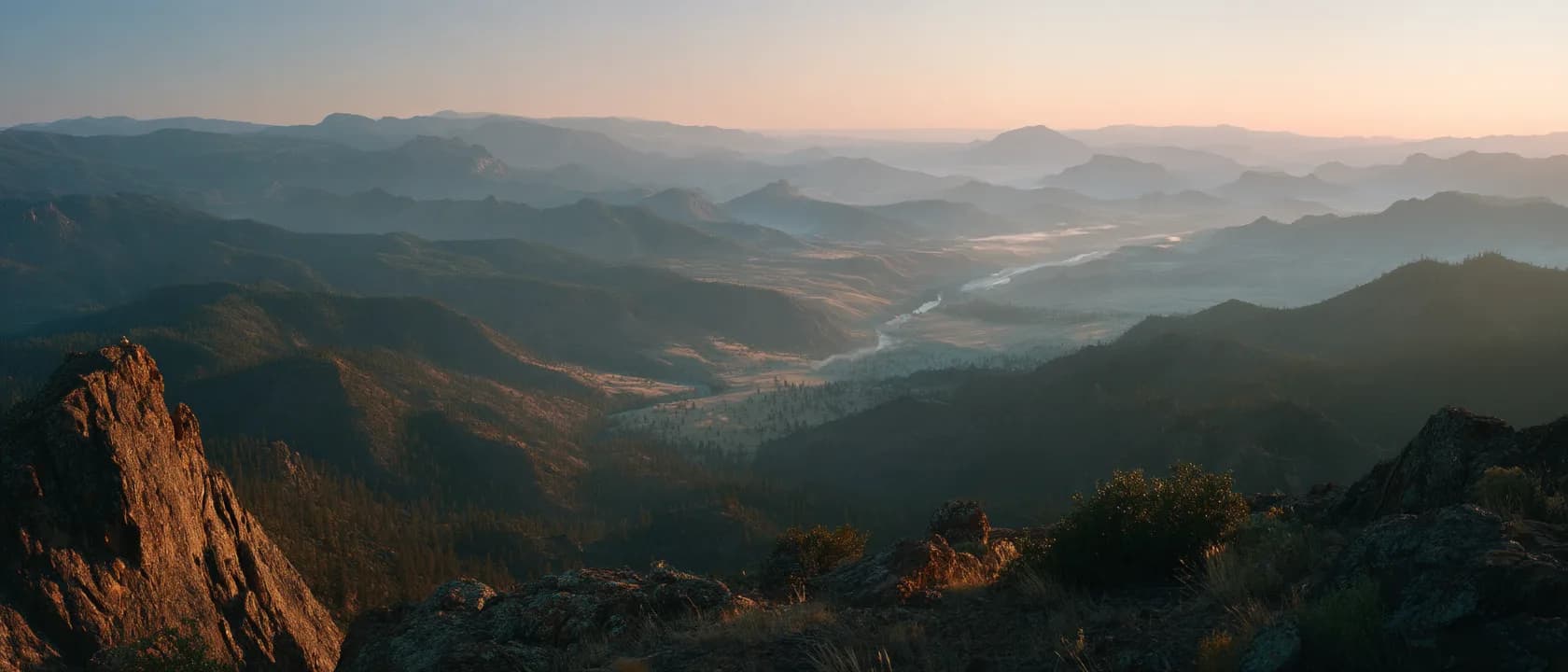 A high ridge overlooking a wide valley and a winding river at dawn