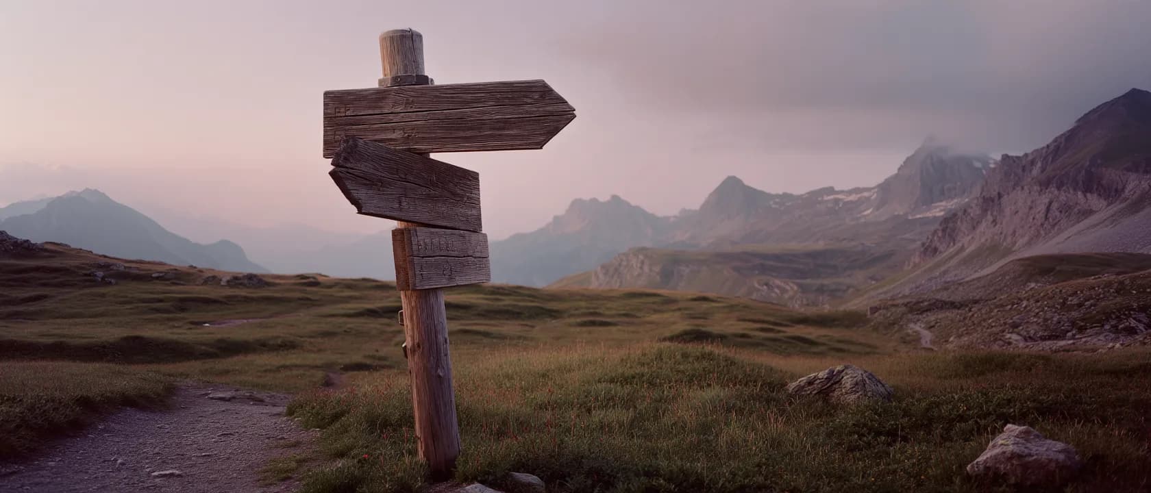 A weathered wooden signpost beside an alpine trail at dusk