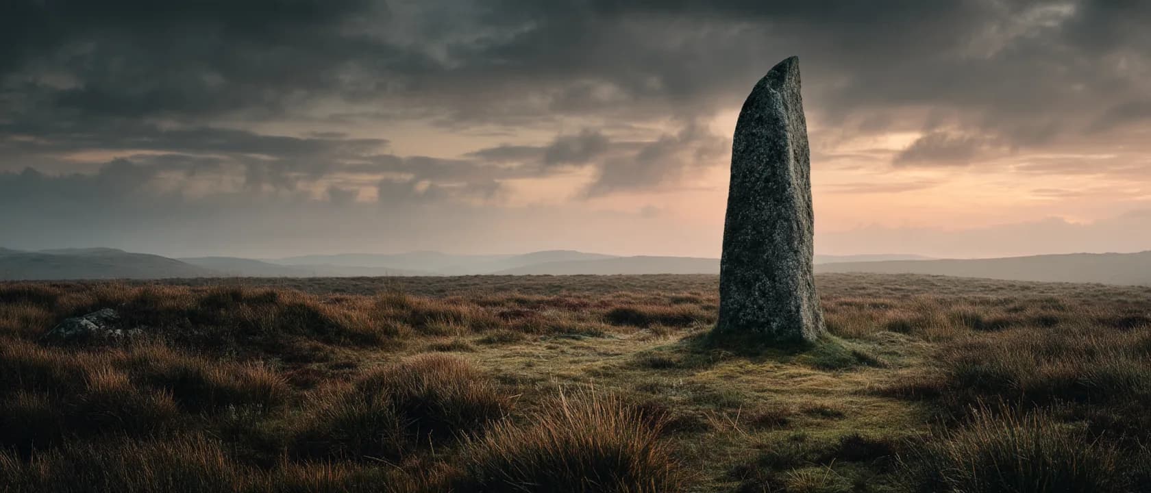 A lone standing stone on open moorland at dusk