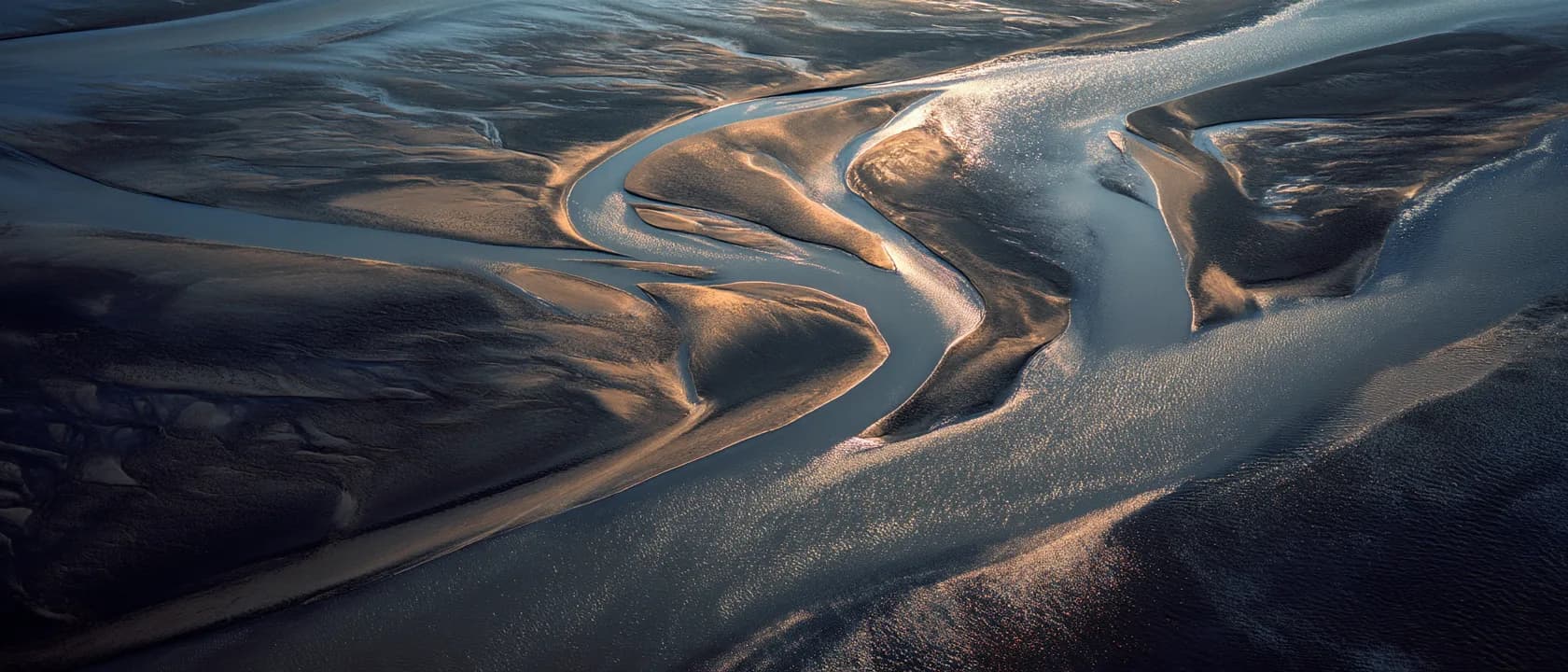 A braided river delta seen from above, its channels traced by the current